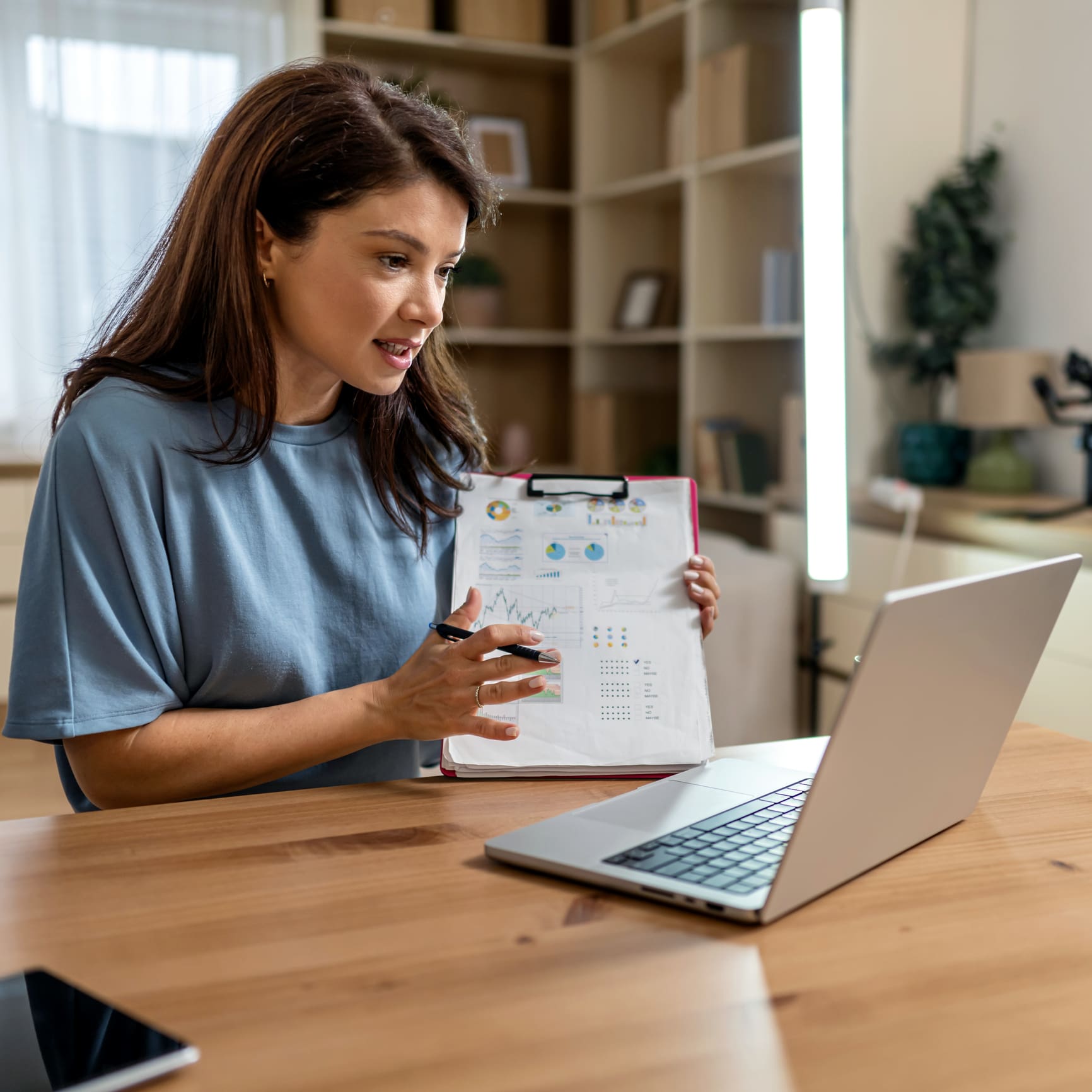 Woman discussing charts during video call.